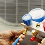Close up of professional worker holding pressure indicators used for checking air conditioner freon tank in need of maintenance. Licensed serviceman using manifold gauges to check refrigerant levels
